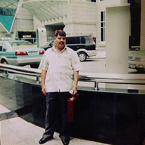 Mohammed Siddique Khan standing in front of skyscraper with briefcase in hand in Shanghai