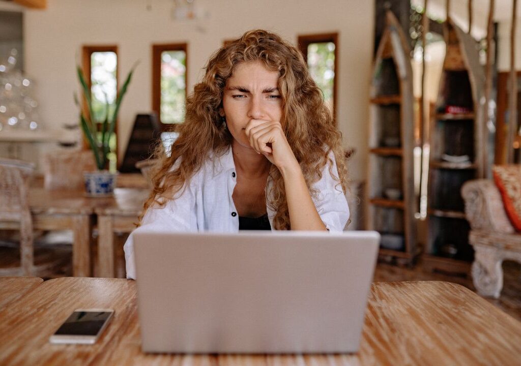 women sitting on a chair and contemplating looking at her laptop