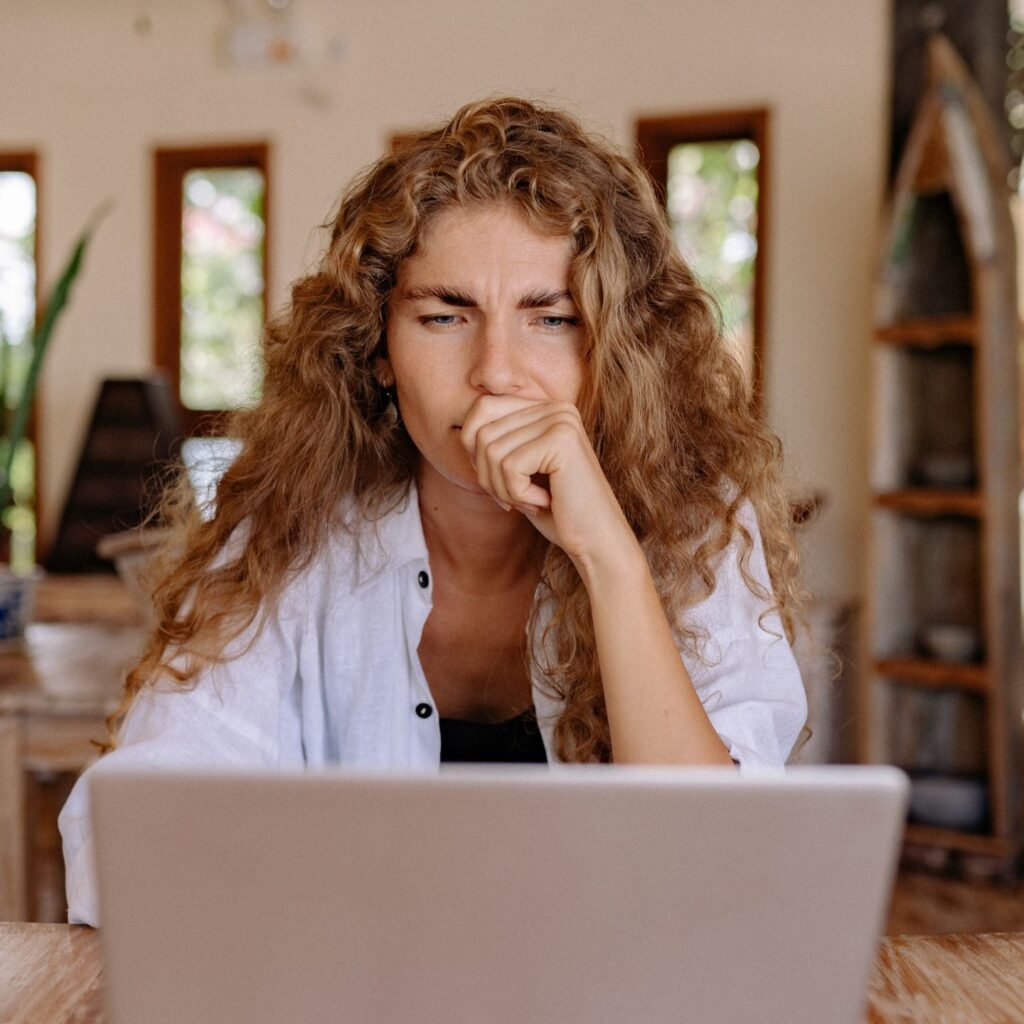 women sitting on a chair and contemplating looking at her laptop