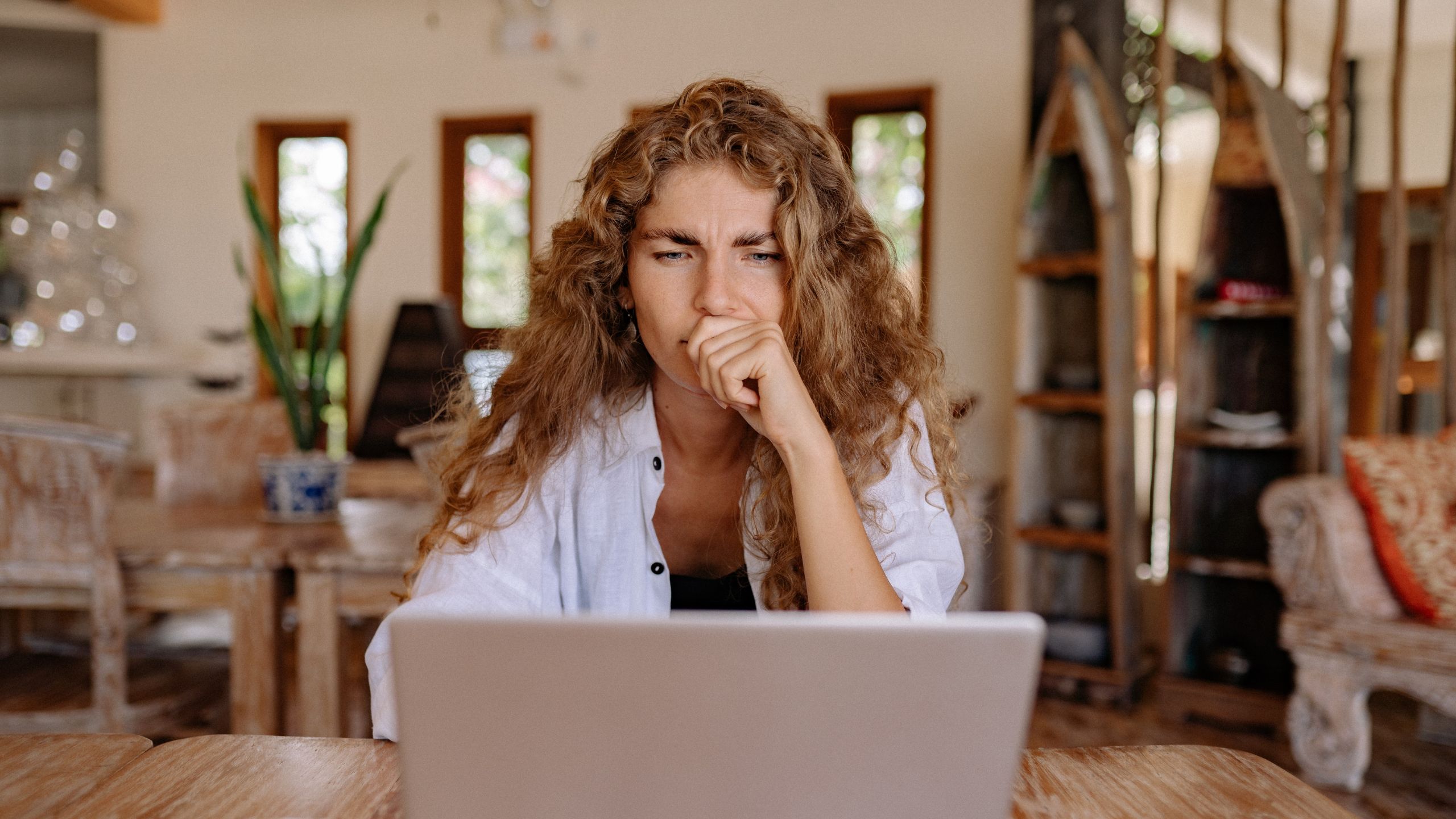 women sitting on a chair and contemplating looking at her laptop