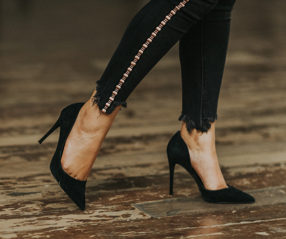 women in black jeans wearing black colour stilletos standing on a wooden floor